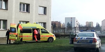 Zlomené zábradlí balkonu a bezvládný muž, ležící před domem