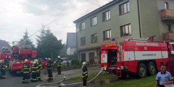 Dědečka s vnoučkem museli hasiči z hořící bytovky na zem snést pomocí výškové techniky